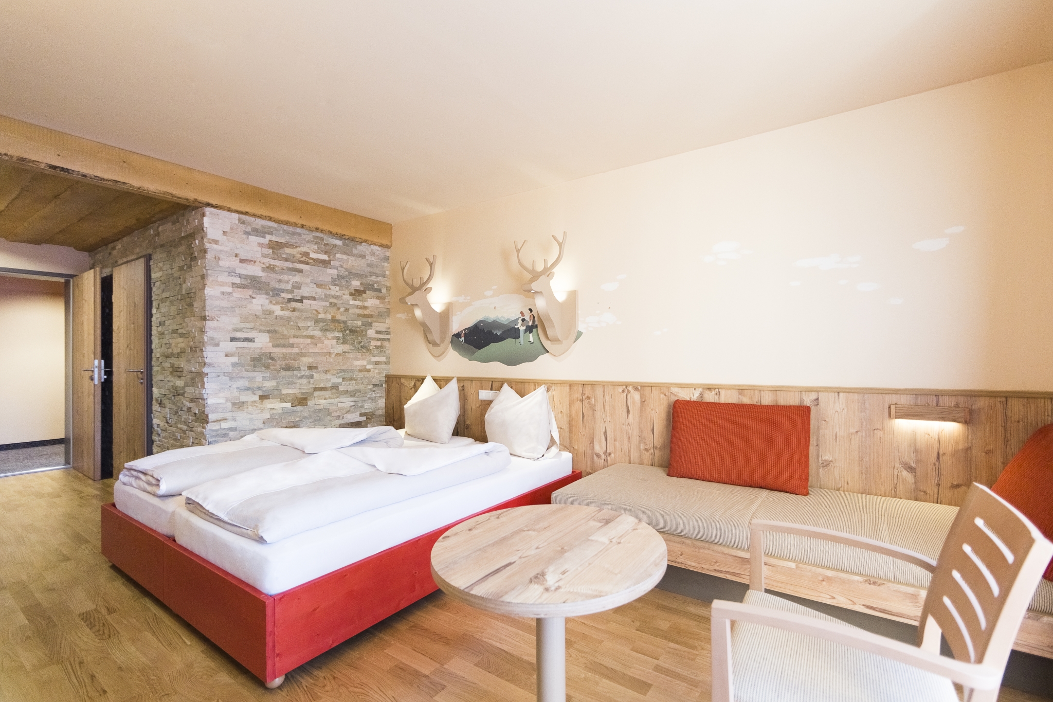 Ihr seht ein Doppelbett in einem Doppelzimmer im JUFA Hotel Annaberg***s mit einer Sitzgelegenheit. JUFA Hotels bietet erholsamen Familienurlaub und einen unvergesslichen Winterurlaub.