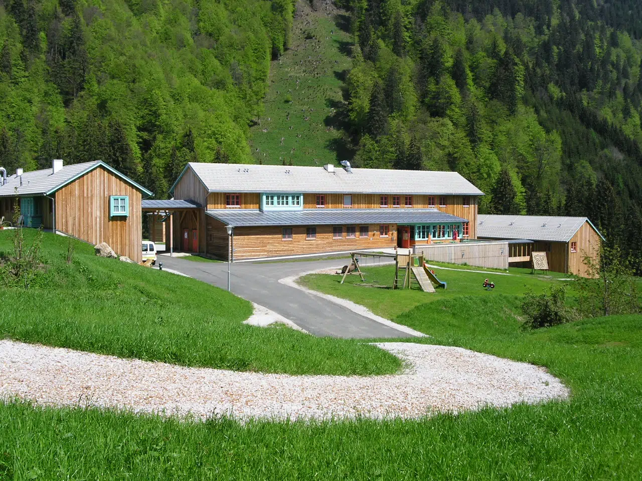Aussenansicht mit Zufahrt im Sommer vom JUFA Hotel Eisenerz Almerlebnis. Der Ort für erholsamen Familienurlaub und einen unvergesslichen Winter- und Wanderurlaub.